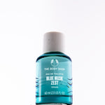A 60ml bottle of The Body Shop Blue Musk Zest Eau de Toilette, featuring a translucent teal blue liquid and a speckled off-white cap, set against a plain white background.