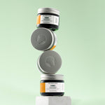 Stack of The Body Shop Glow Boosting Moisturiser jars on a light green background
